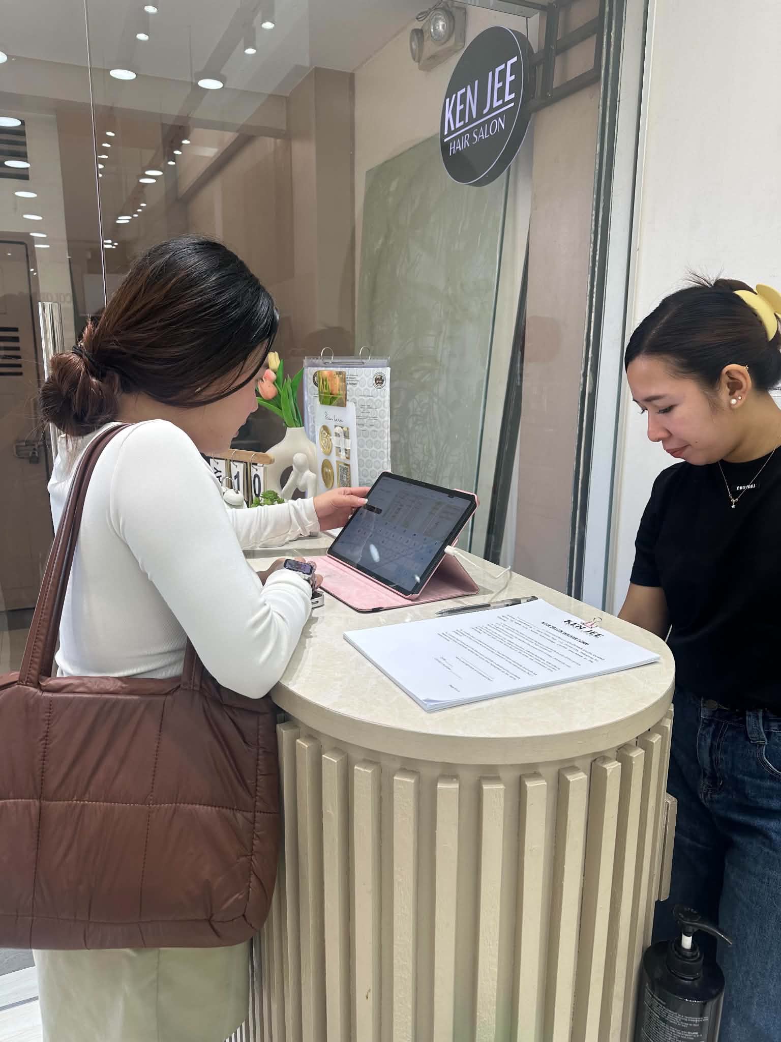 A walk-in client tapping the Kairo kiosk tablet at Kenjee Hair Salon